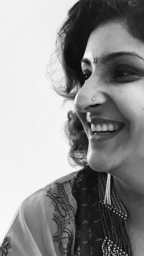 Black and white profile photo of a woman with decorative earrings and jewelry.