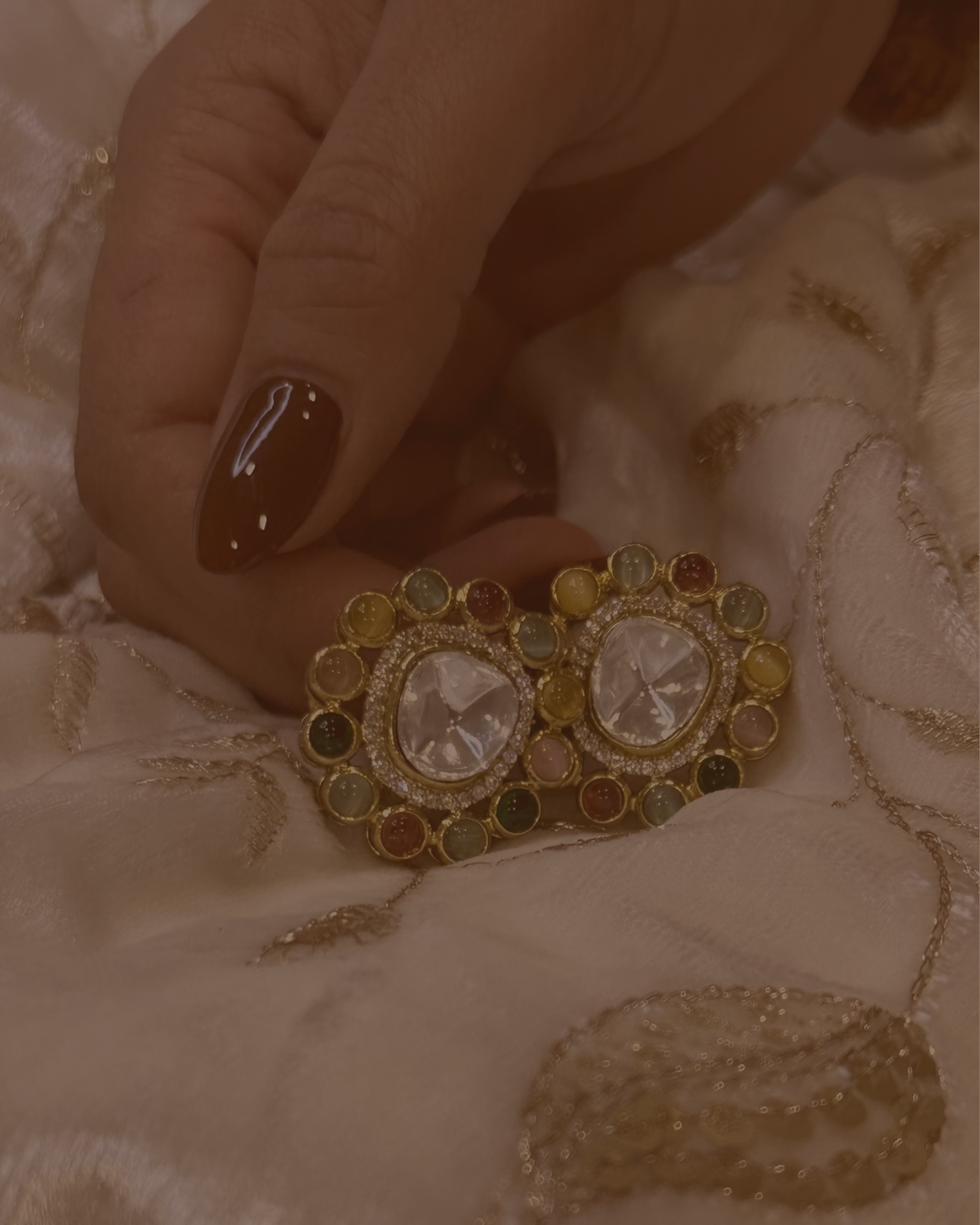 Decorative earrings with gemstones on a textured fabric background