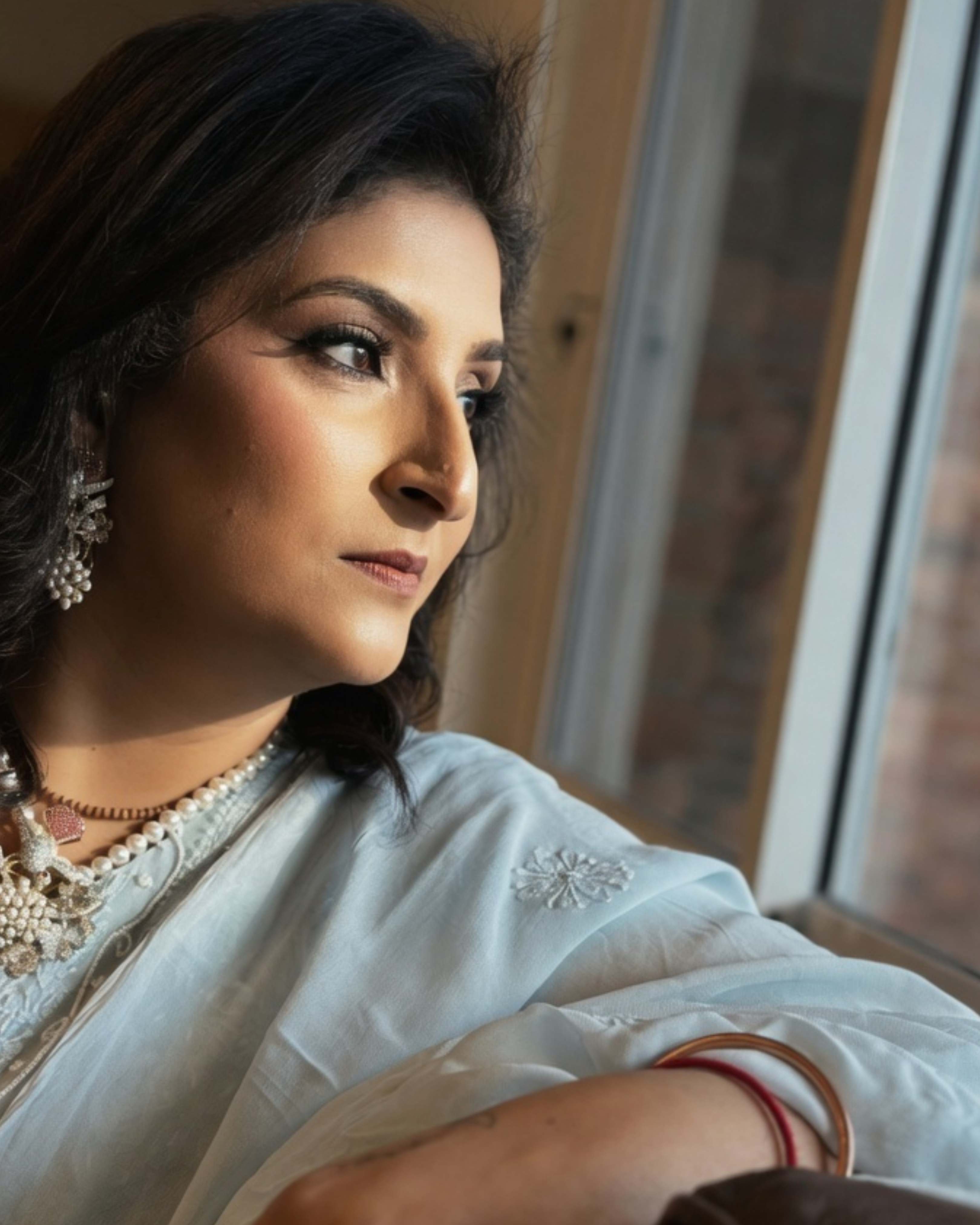 Woman in traditional attire sitting by a window