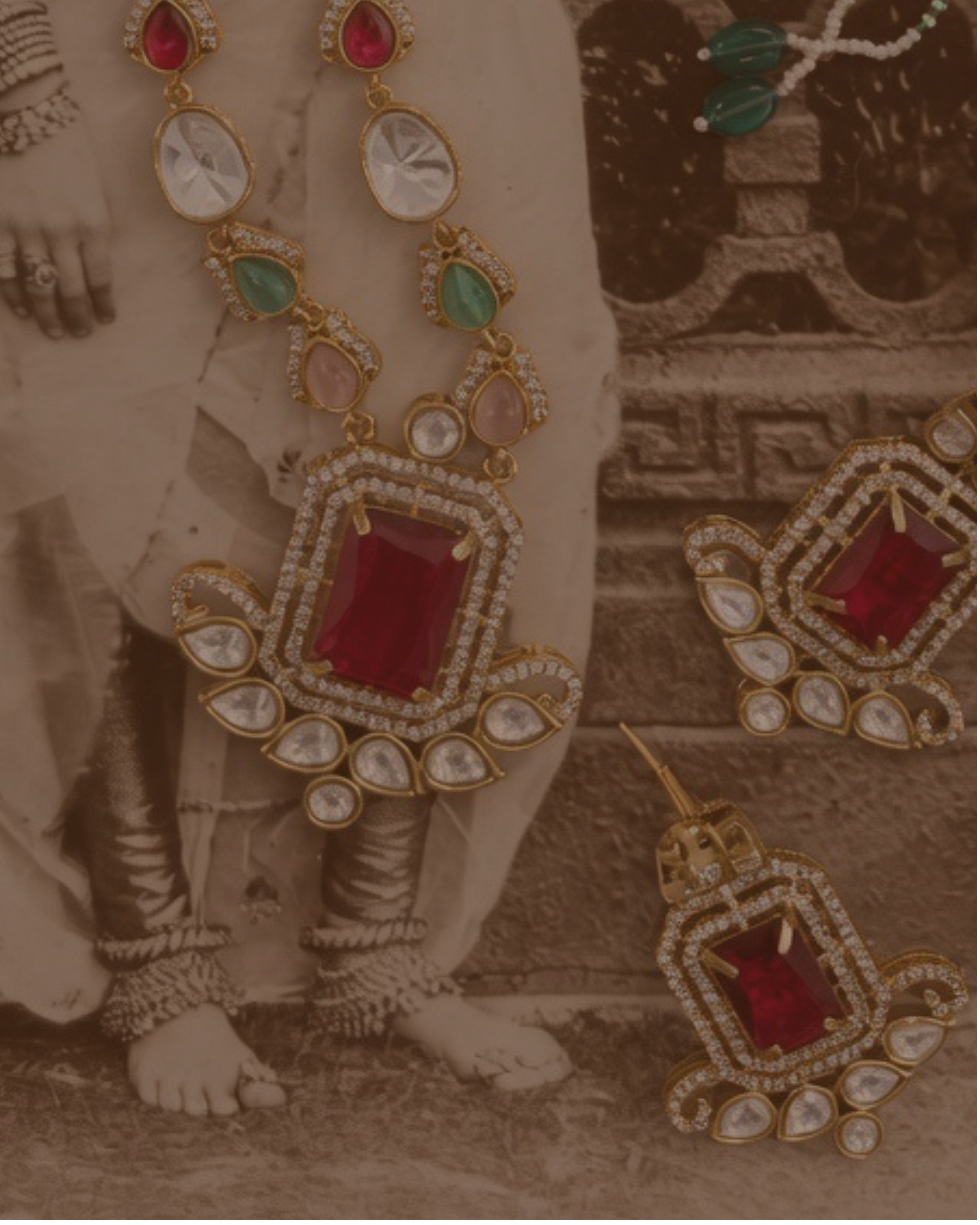 Traditional jewelry with red and green gemstones on a sepia-toned background