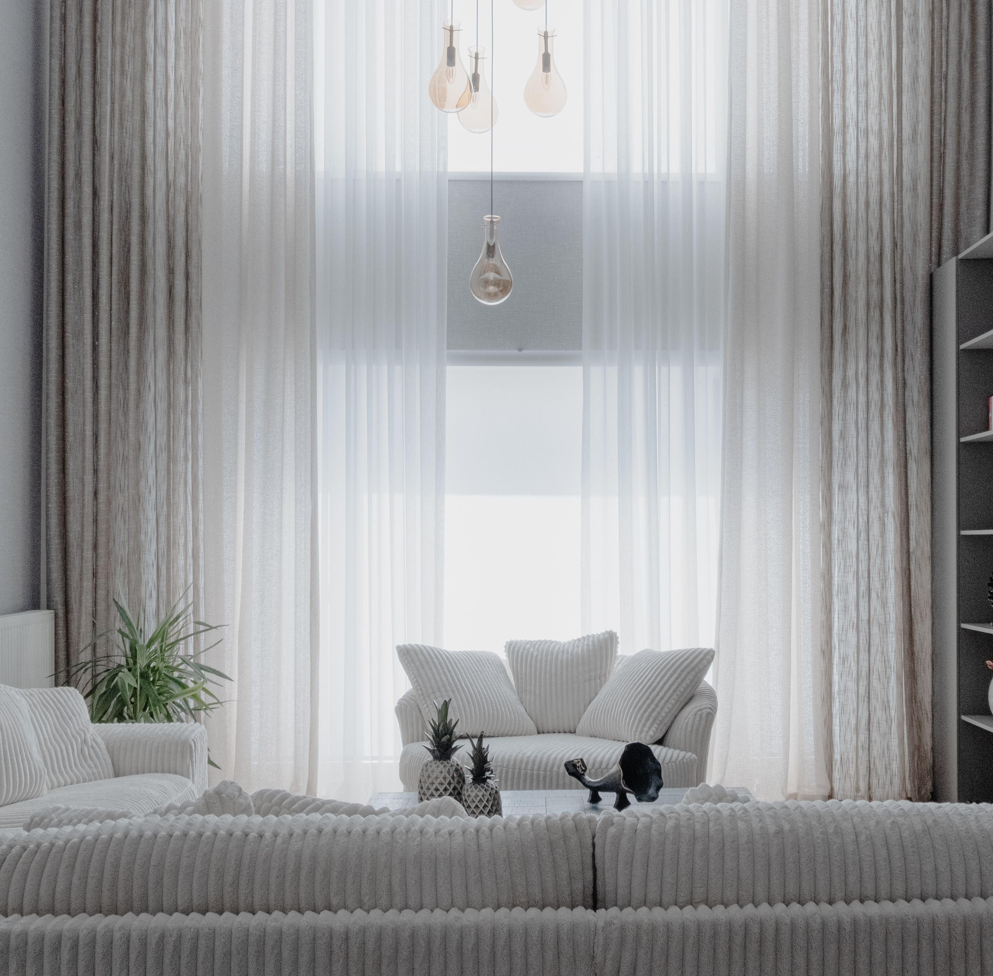 Modern living room with gray sofas, white curtains, and decorative items.